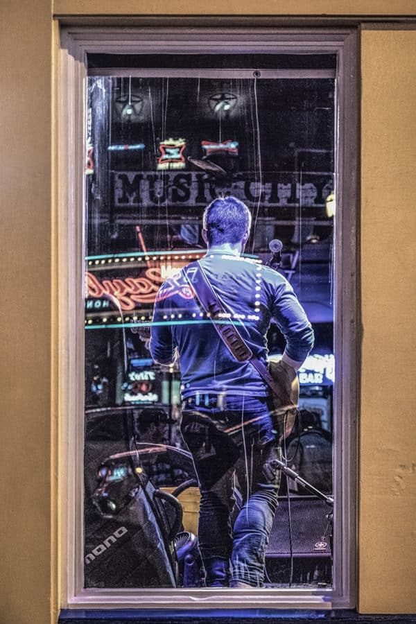Gutar player in Nashville, Tennessee looking through a bar window