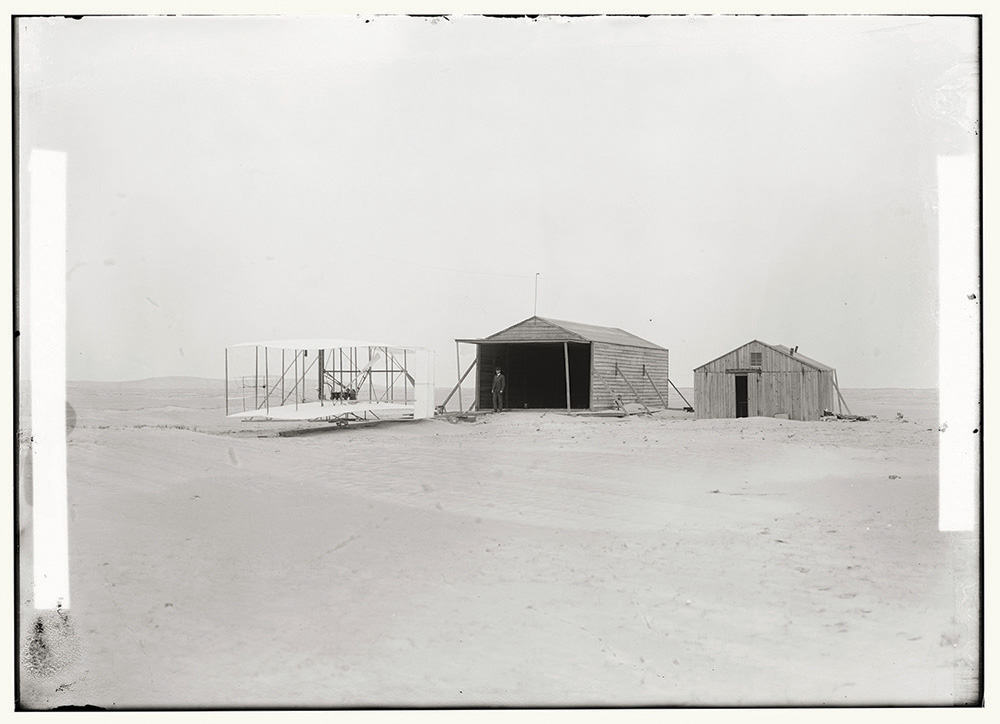 Wright Brothers photograph 1903 machine and large camp building where it was housed, and smaller building used as a workshop and living quarters at Kill Devil Hills